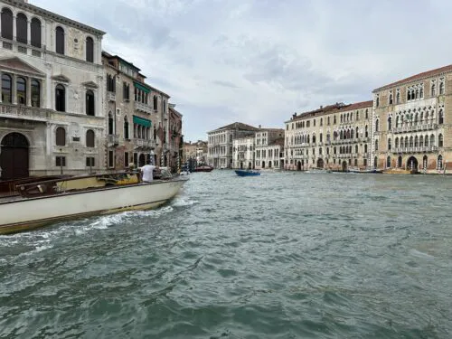 Boat traveling on the Grand Canal between historic Venetian palaces in Venice Italy