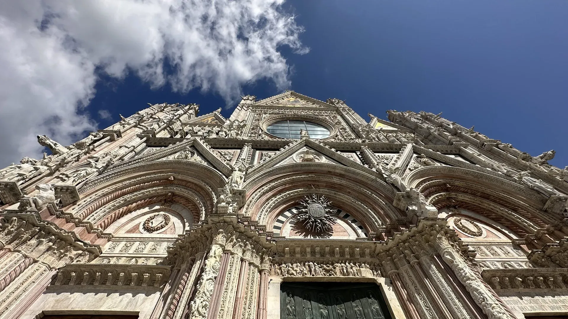 Fascade of the Duomo di Siena showing detailed stonework in black, white and red marble.
