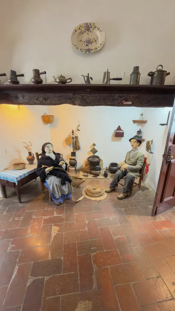 Recreated domestic life scene with figures, cookware, and household objects inside the Loulé Castle Museum.