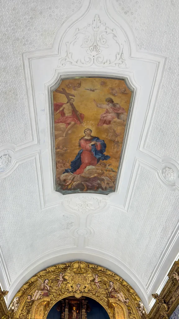 Religious ceiling fresco surrounded by decorative plasterwork inside Ermida de Nossa Senhora da Conceição in Loulé, Portugal.