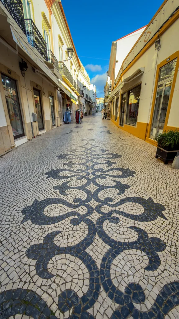 Decorative black and white calçada paving on a pedestrian shopping street in Loulé, Portugal.