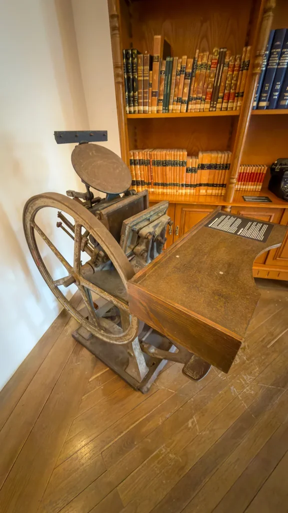 Antique printing press displayed beside old books inside the Loulé Castle Museum in Portugal.