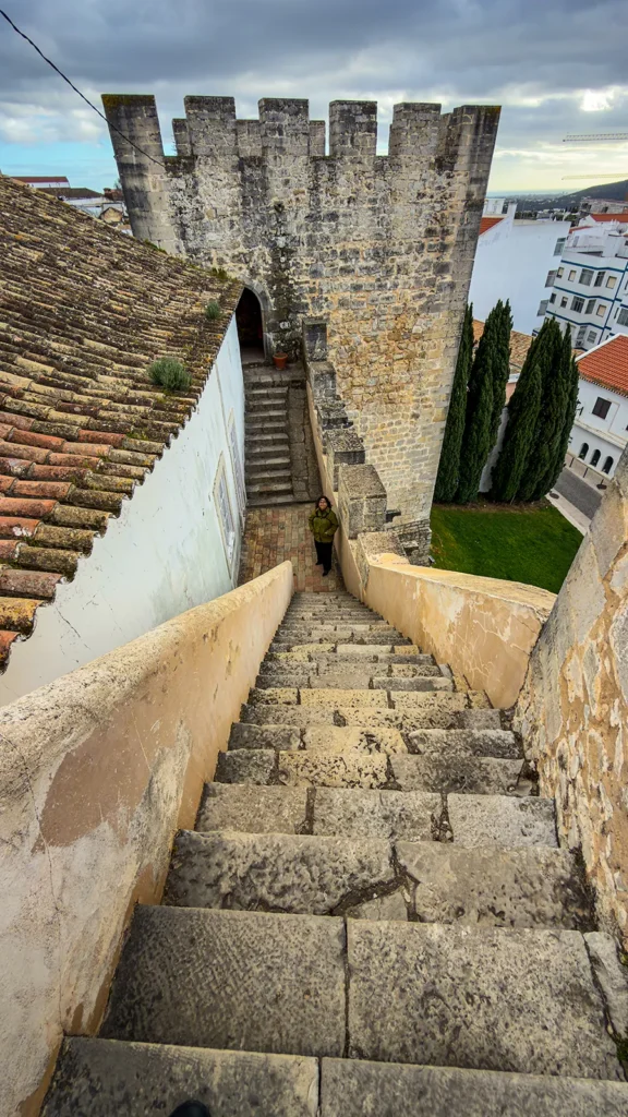 Steep stone stairs inside Castelo de Loulé leading down toward the castle tower and courtyard.