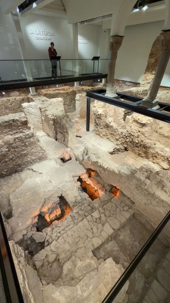 Archaeological remains of the Islamic Baths of Loulé showing the tepid room, cold room, stone walls, columns, and illuminated underfloor spaces.