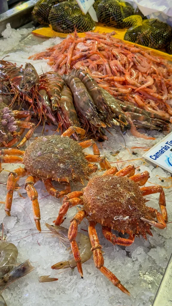 Fresh seafood including shrimp and crabs displayed on ice inside Mercado de Loulé in Portugal.
