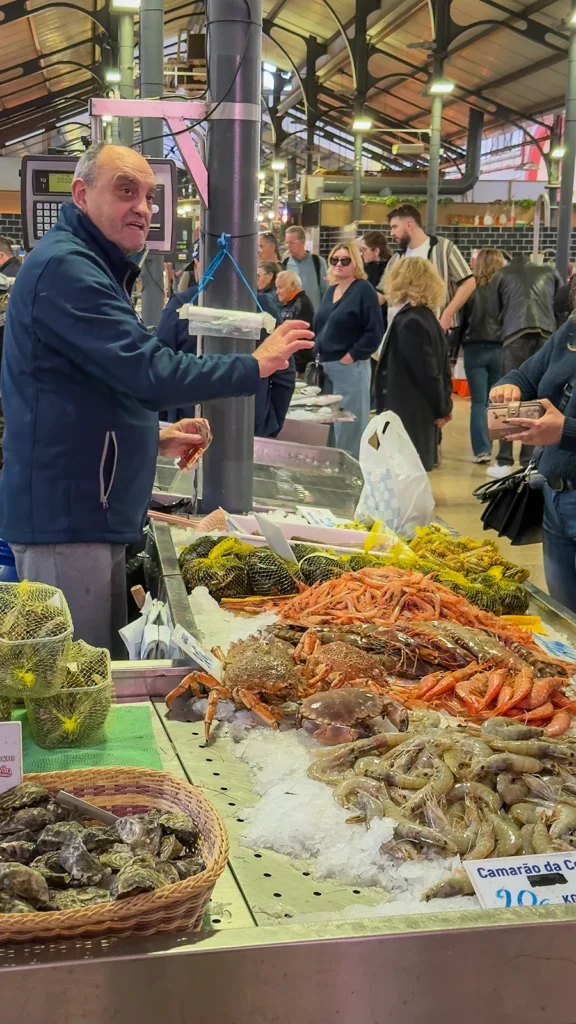 Seafood vendor serving customers at a fish counter inside Mercado de Loulé in Portugal.