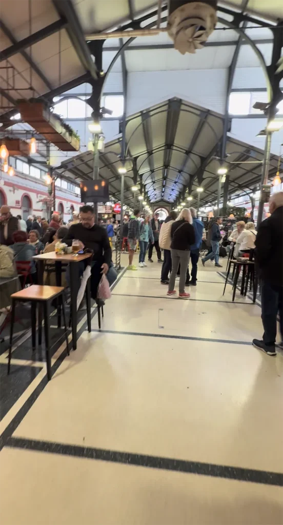 People eating and walking inside Mercado de Loulé, showing the market hall as a lively social gathering place in Portugal.