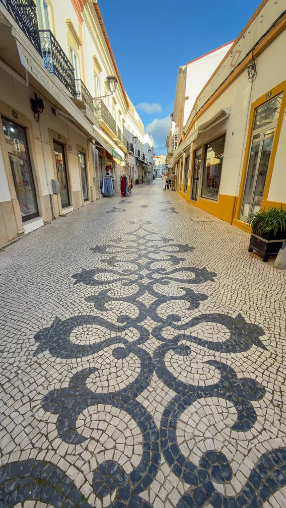 Decorative black-and-white calçada pavement on a pedestrian shopping street in Loulé, Portugal.