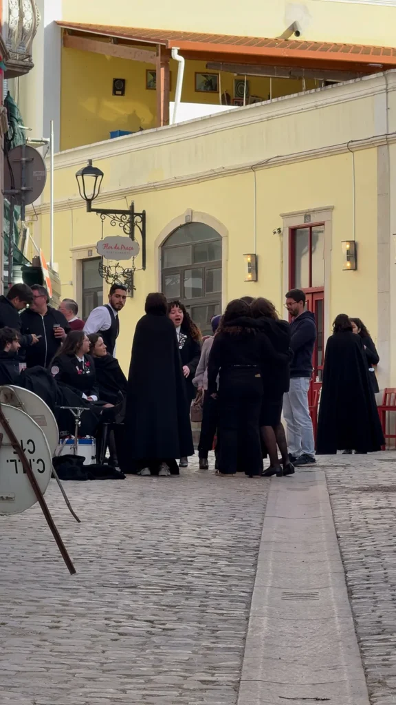 Group of people in dark traditional clothing gathered outside a restaurant on a cobbled street in Loulé, Portugal.