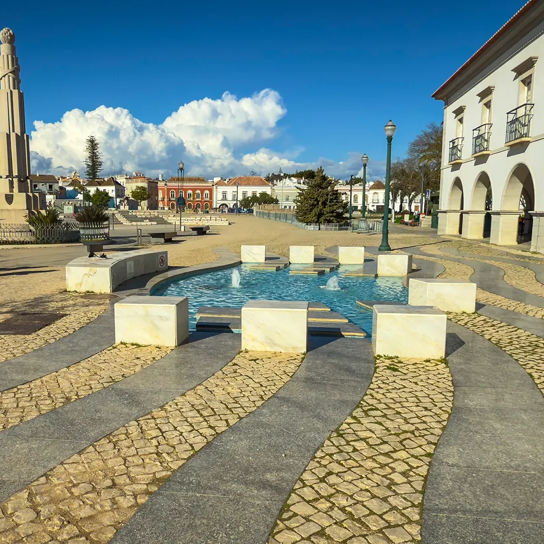 Place centrale piétonne à Tavira, avec pavage en calçada, vastes espaces ouverts et soleil hivernal de l’Algarve.